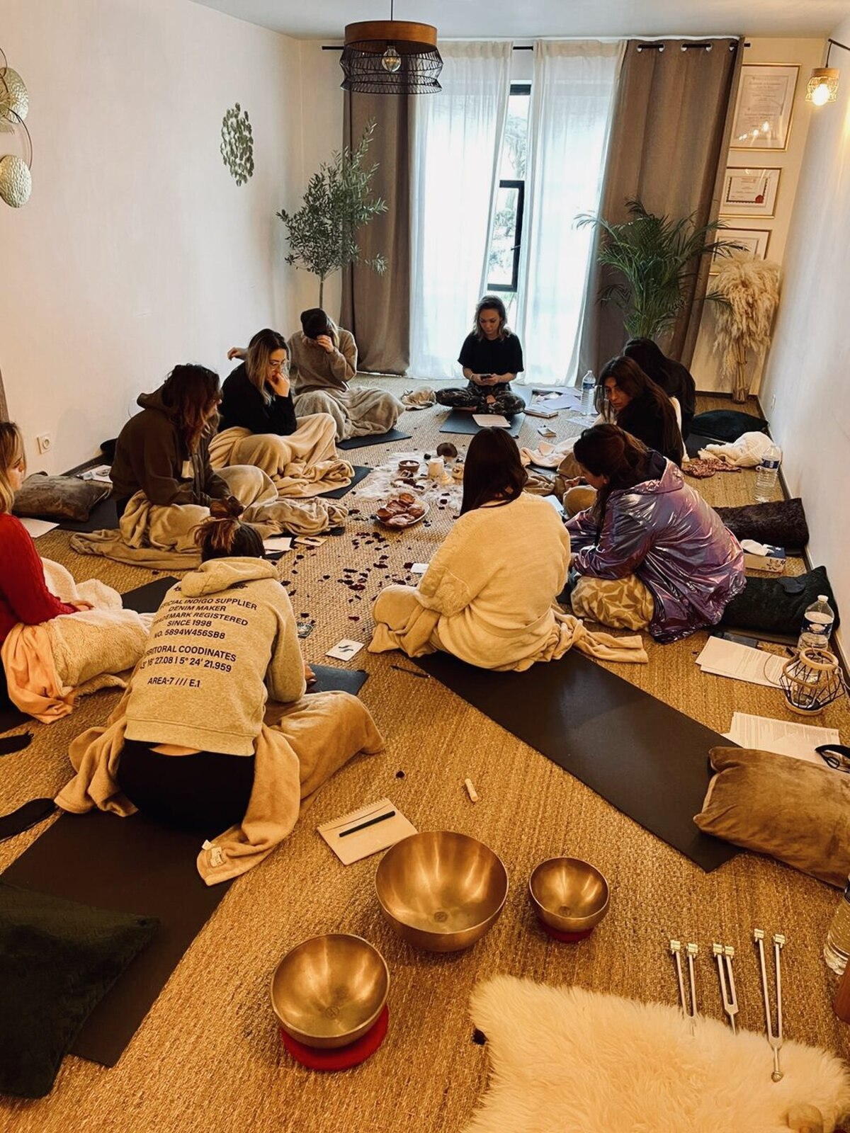 Un de ses ateliers : un groupe assis en cercle sur des tapis, bols chantants au premier plan.